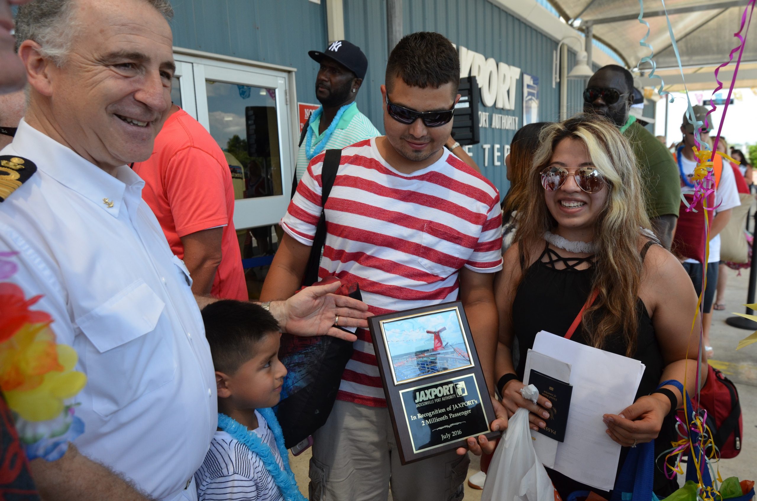 A family poses with a plaque commemorating JAXPORT's two millionth cruise passenger